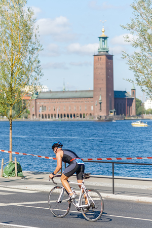 STOCKHOLM - AUG 23, 2015: Triathlete with the Stockholm waterfront and city hall in background at the ITU World Triathlon event in Stockholm.のeditorial素材