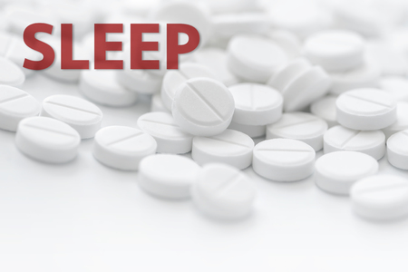 White tablets in closeup on white background with text SLEEP in red. Bright white background.の写真素材