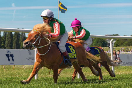 STOCKHOLM, SWEDEN - JUNE 6, 2016: Two fast ponnies and young jockeys at Nationaldags Galoppen at Gardet.のeditorial素材