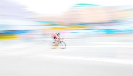 Cyclist in extreme motion blur capture in bright and vivid colors on a city road. Wide angle shot.