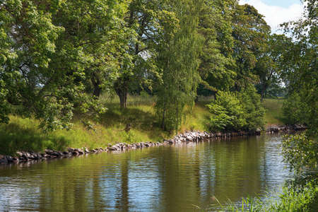 Lush riverside with reflections. Swedenの写真素材