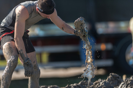 STOCKHOLM, SWEDEN - AUG 27, 2016: Man cleaning the shoes from mud at the Mud Charge by Backstrom at the Tough Viking event at Gardet in Stockholm.のeditorial素材