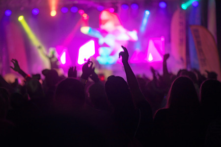 STOCKHOLM, SWEDEN - SEPT 18, 2016: Hands and arms silhouette of happy people infront of the stage at the Color Run Night Edition in Stockholm.のeditorial素材
