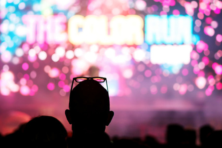 STOCKHOLM, SWEDEN - SEPT 18, 2016: Silhouettes of happy people infront of the stage at the Color Run Night Edition in Stockholm. The Color Run in unfocused text.のeditorial素材