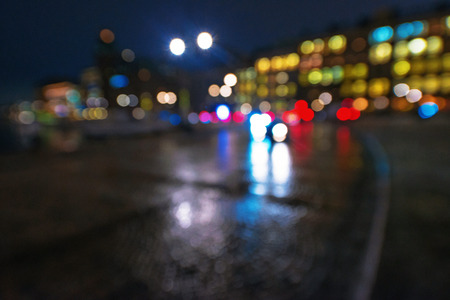 Defocused cars during night with colorful lights and reflections from the wet street. Sw