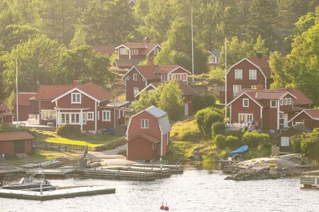 STOCKHOLM, SWEDEN - JUNE 19, 2016: Small picturesque coastal village in the swedish archipelago with red houses. Summerhazeのeditorial素材