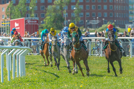 STOCKHOLM, SWEDEN - JUN 6, 2017: Horses with jockeys out of a curve in fast pace at Nationaldagsgaloppen at Gardet.のeditorial素材