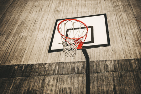 Basketball hoop surrounded with grey concrete in a rough area. High contrast and filteredの写真素材