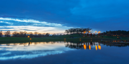 Panoramic viev of the Woodland cemetary in the pond with fires lighten up during with reflections during the evening, blue sky. Skogskyrkogarden, Sweden at the All ains night the 4th of Novemberのeditorial素材