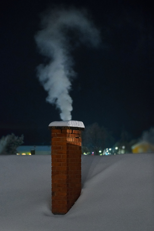 Chimney with white smoke during an cold winter evening. Swedenの写真素材
