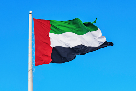 Flag of the United Arab Emirates, UAE waving during a clear blue sky.