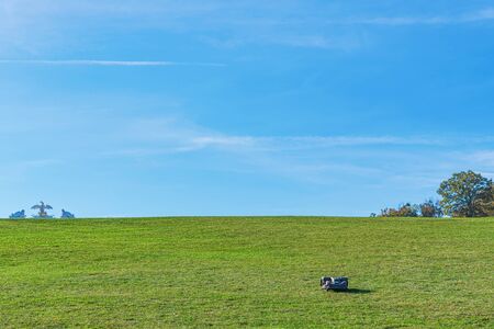 A lonely automatic electric lawnmover working thru the wast areas of lawn at Schoenbrunn in Vienna. The Gloriette visible at the horisont.の写真素材