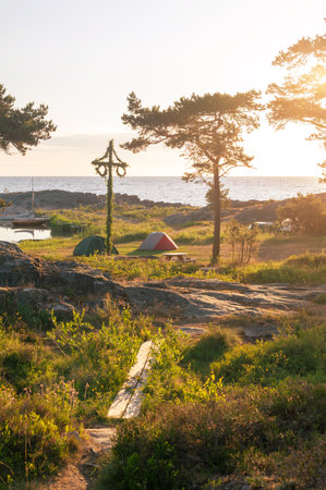 Sunrise of a classic midsommer pole with small tents with campers at the coast line of Roslagen. Swedenの写真素材