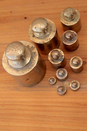 Antique weights from an old scale, made of brass, on a wooden backgroundの写真素材