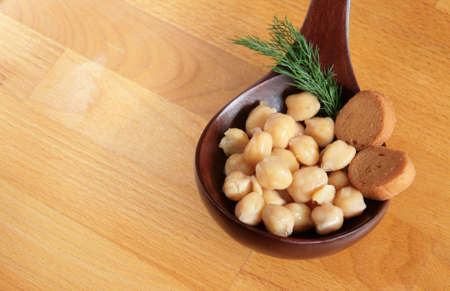 Chickpeas with bread croutons in a wooden spoon and on a wooden tableの写真素材
