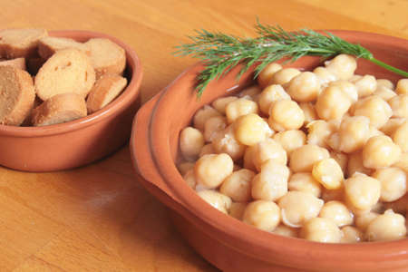 A bowl of chickpea soup in an earthenware bowl, with bread crouton on its sideの写真素材