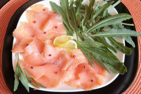 A dish of smoked salmon with red pepper and rocketの写真素材