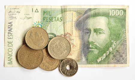No longer in circulation Spanish pesetas, one banknote and some old coins above, isolated on whiteの写真素材