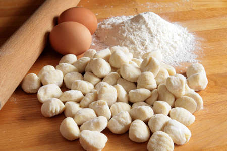 Raw potato gnocchi with eggs, flour and rolling pin on a wooden tableの写真素材