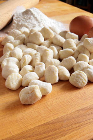 Raw potato gnocchi with eggs, flour and rolling pin on a wooden tableの写真素材