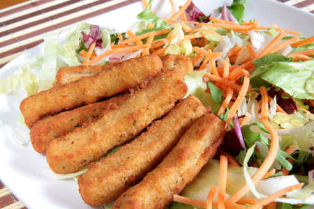 A delicious and colorful plate of deep-fried chicken sticks with mixed saladの写真素材