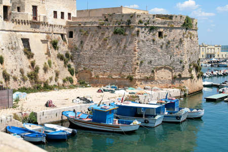 Back side of the Angevin castle in Gallipoli, Salento region (Apulia) with the tower and some fishing boats in the harbor.の写真素材