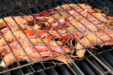 King prawns coated with breadcrumbs while cooking on a barbecue grillの写真素材