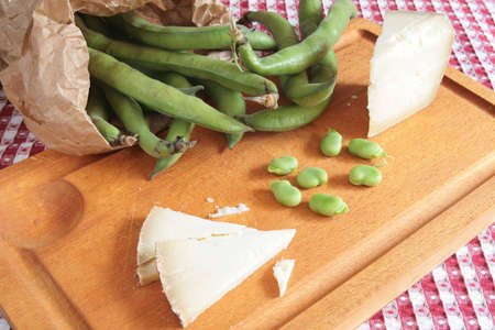 Wooden chopping board with fava beans and sheep's milk cheeseの写真素材