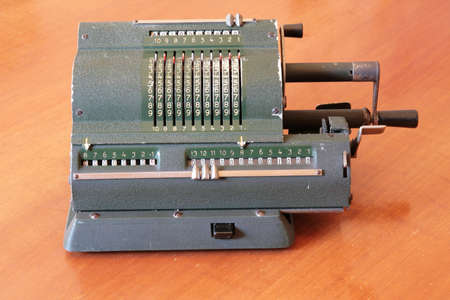 Vintage calculator, worn out, on a wooden desk. Italian model from the 1940-1950sの写真素材