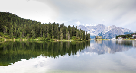 lake in the Alps where mountain peaks and fir woods are reflectedの写真素材