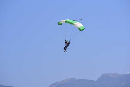 parachutist descends against a blue sky, in the background the mountainsの写真素材