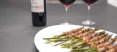 Grilled wild asparagus wrapped in bacon. Red wine and gobletsの写真素材