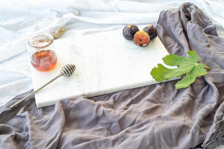 Autumn breakfast still life. Cup of coffee, fig fruit, bread with butter and jam on wooden chop board. Breakfast in bed, fall food concept.の写真素材