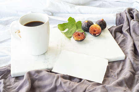 Autumn breakfast still life. Cup of coffee, fig fruit, bread with butter and jam on wooden chop board. Breakfast in bed, fall food concept.の写真素材