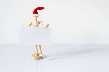 Christmas blank greeting card mock-up scene. Wooden mannequin posing on greeting card or gift list with red Santa Claus hat.の写真素材