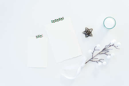 Christmas blank greeting card mockup scene. Festive winter wedding composition.Candle, Christmas decoration on white table.Flat lay, top viewの写真素材