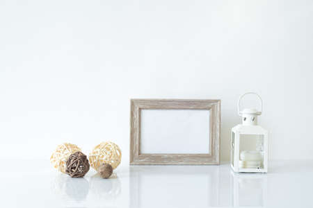 Mock up wooden frame with Christmas lantern and decorations on shelf. Empty portrait frame against a white wallの写真素材