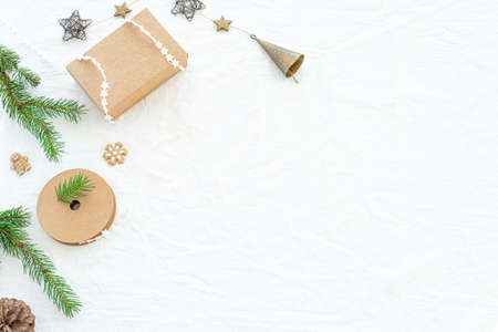 Christmas decorations composition. Christmas greeting card mock-up scene. Gift christmas box with star ribbon, fir branch, copper decorations. White linen background.Copy space, top view, flat layの写真素材