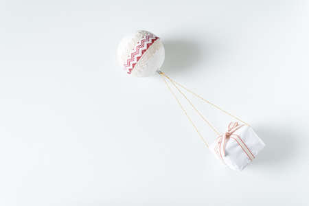 Christmas present hanging on a Christmas ball.Hot air balloon carrying the gift box in flight.Copy space, top view, flat layの写真素材