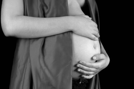 Young woman protecting her pregnant belly with her hands.の写真素材
