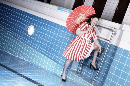 Pretty woman wearing a summer dress posing in poolの写真素材