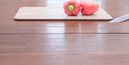 Red bell pepper and knife on cutting board on wooden table background.の写真素材