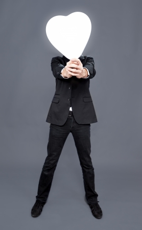 Man holding heart balloon in front of his faceの写真素材