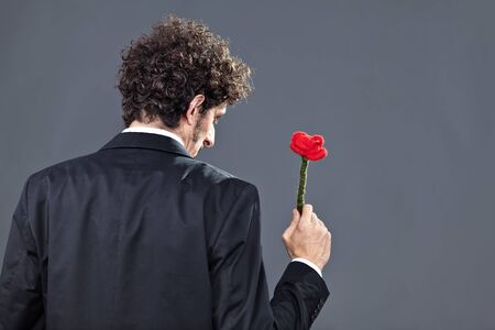 Boy is donating a fabric red rose while facing on his back
の写真素材