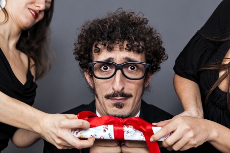 two girl disputing one present from a single boyの写真素材