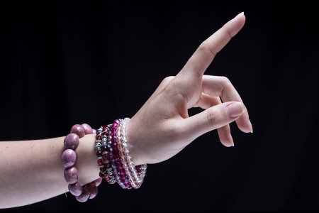 Female hand, isolated on black background, is wearing some ornamentsの写真素材