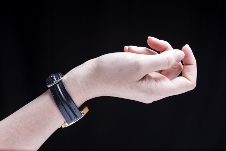 Female hand, isolated on a black background, is wearing a wrist watchの写真素材