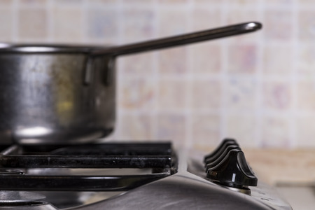 Detail of a stove knob with a pot out of focus on the backgroundの写真素材