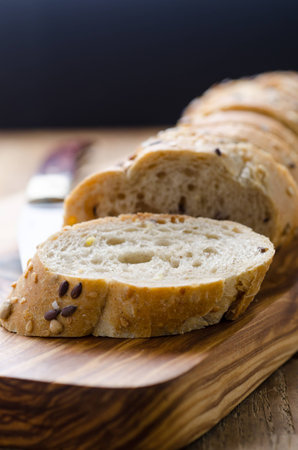 bread with seeds on a wooden board and knife