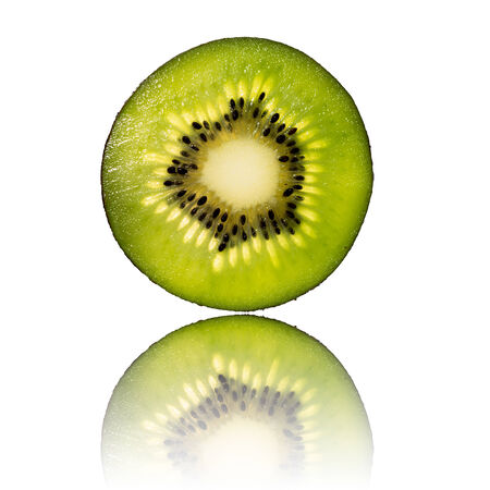 green kiwi slice isolated on white background back lighted and reflectionの写真素材